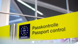 Keliautojai prie pasų kontrolės punkto su Europos Sąjungos ženklu oro uoste.