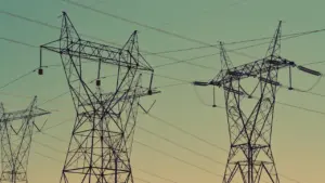 Elektros perdavimo linijų atramos prieš dangų atspindi Lietuvos energetikos infrastruktūros tinklo plėtrą.