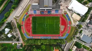 Sporto stadionas su bėgimo takeliais ir veja iš paukščio skrydžio perspektyvos.