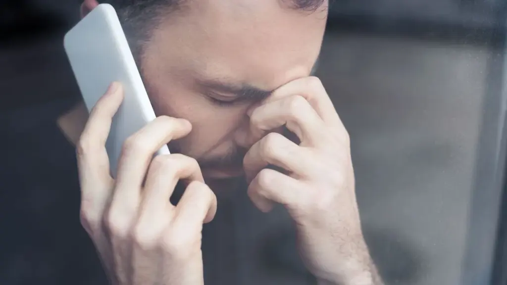 Vargstantis vyras kalba telefonu laikydamas ranką prie kaktos ir atrodo labai pavargęs.