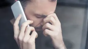 Vargstantis vyras kalba telefonu laikydamas ranką prie kaktos ir atrodo labai pavargęs.